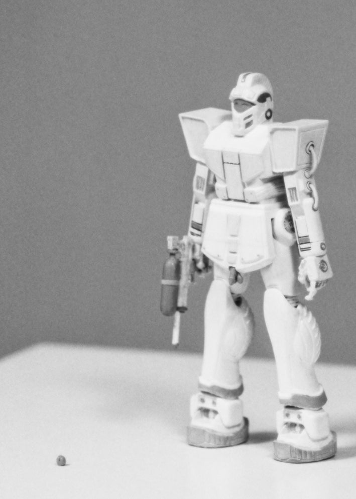 A poster featuring a 3D model of a character in a grayscale color palette, with the model equipped with a gun and a suit-like armor.