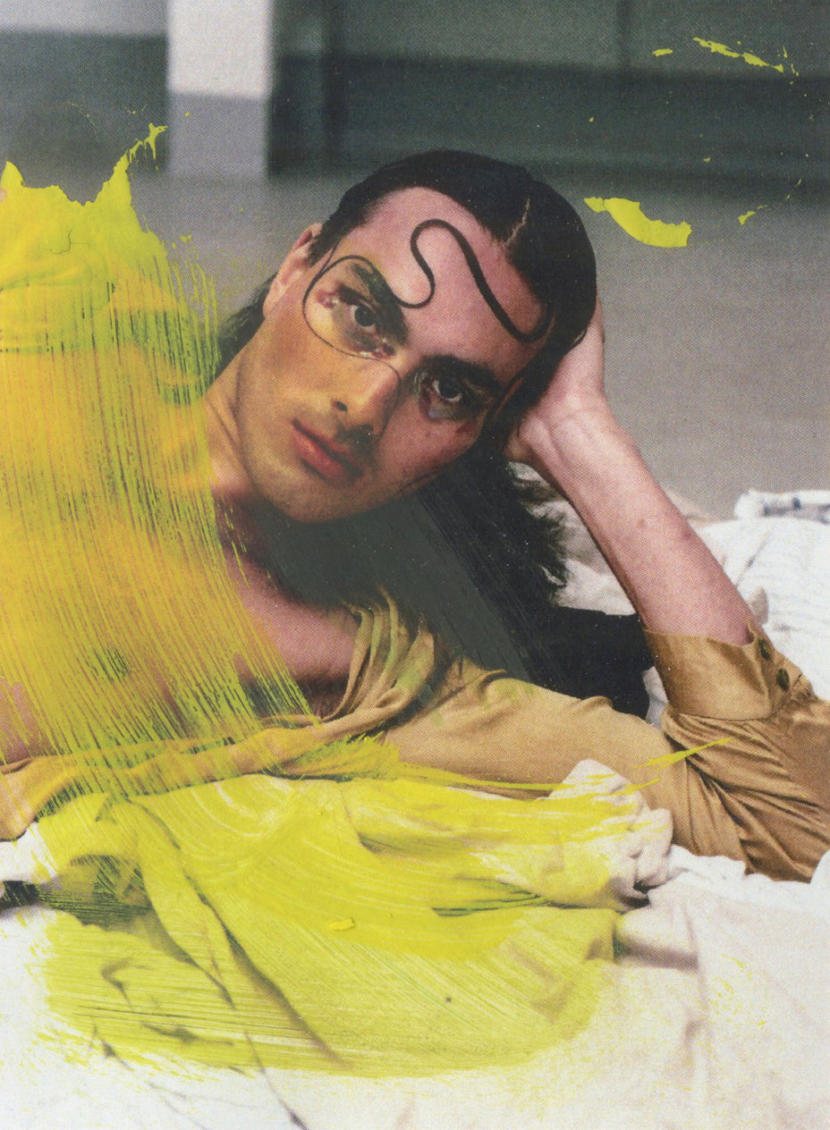 A poster featuring a male model with a contemplative expression, surrounded by yellow and green paint splatters, indicative of an artistic or creative theme.