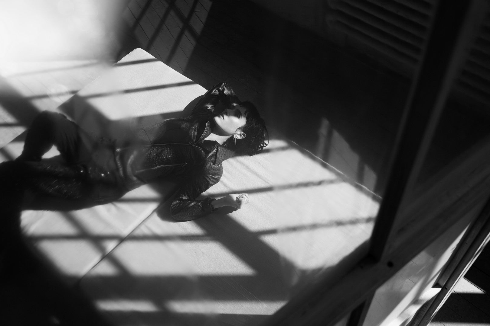 Person lying on a floor with shadows cast by window blinds