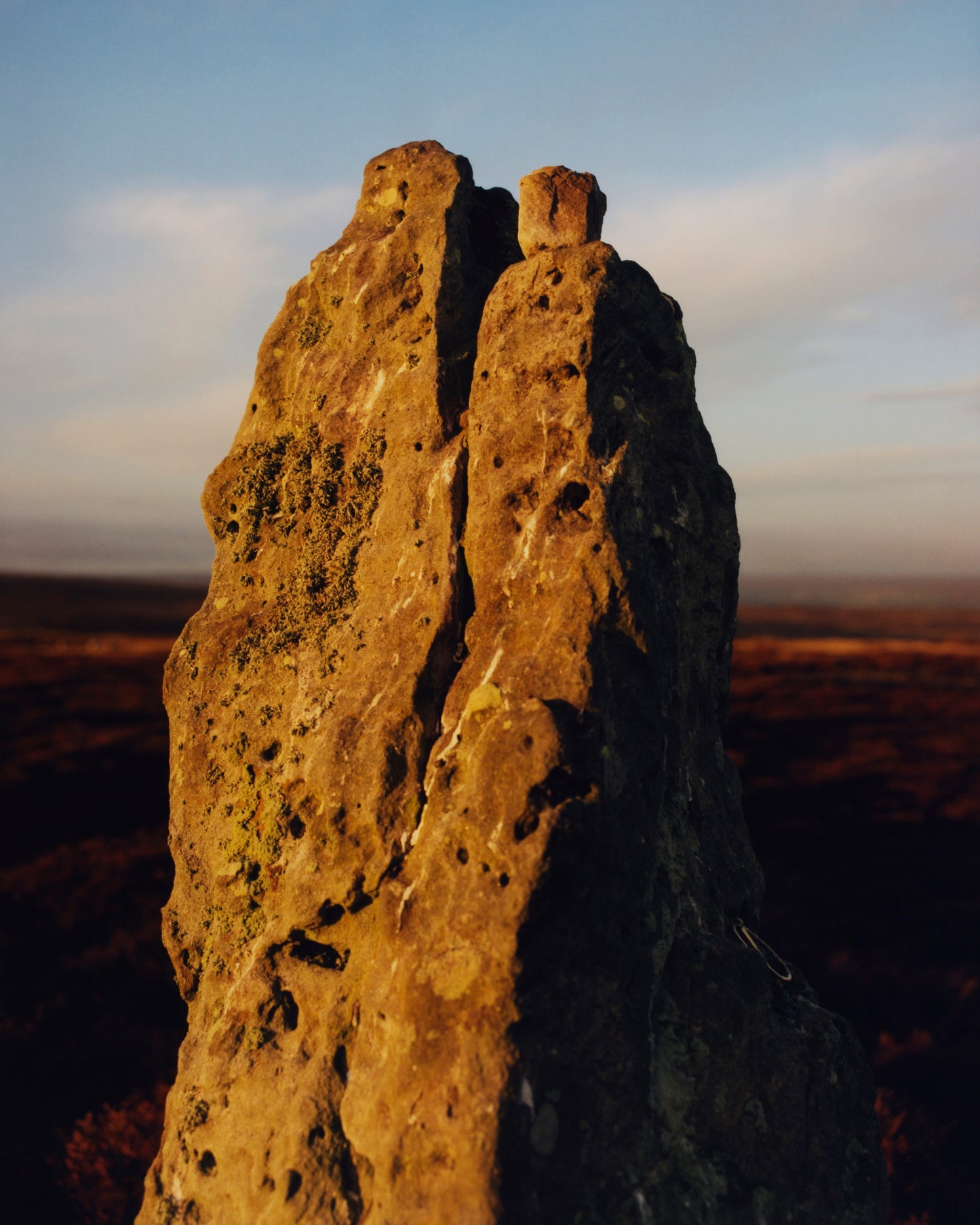 Tall rock formation with a blurred landscape in the background